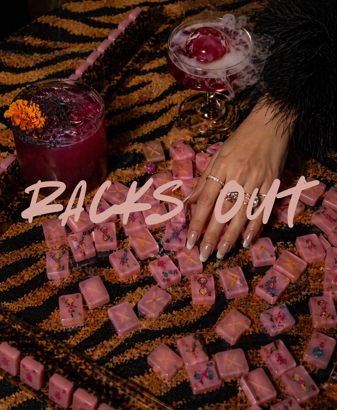 Cocktails and pink mahjong tiles arranged on a tiger-print runner